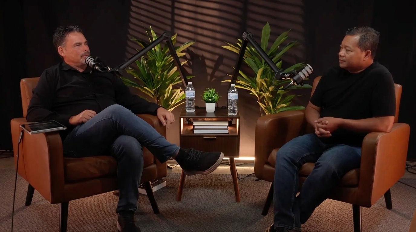 Two guests recording a podcast conversation in the JW studio, seated in tan leather chairs with broadcast microphones