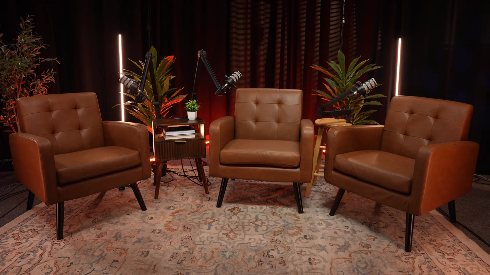 The JW podcast studio set with three tan leather chairs, microphones, and warm lighting